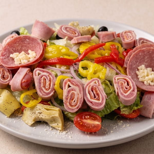 Italian chopped salad topped with rolled deli meats, salami, pepperoncini, roasted peppers, artichokes, olives, tomatoes, and cheese.